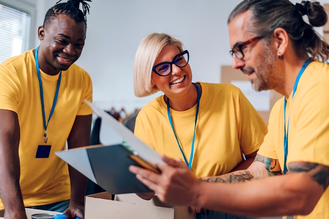 Three people in yellow shirts and blue lanyards looking at a document together.