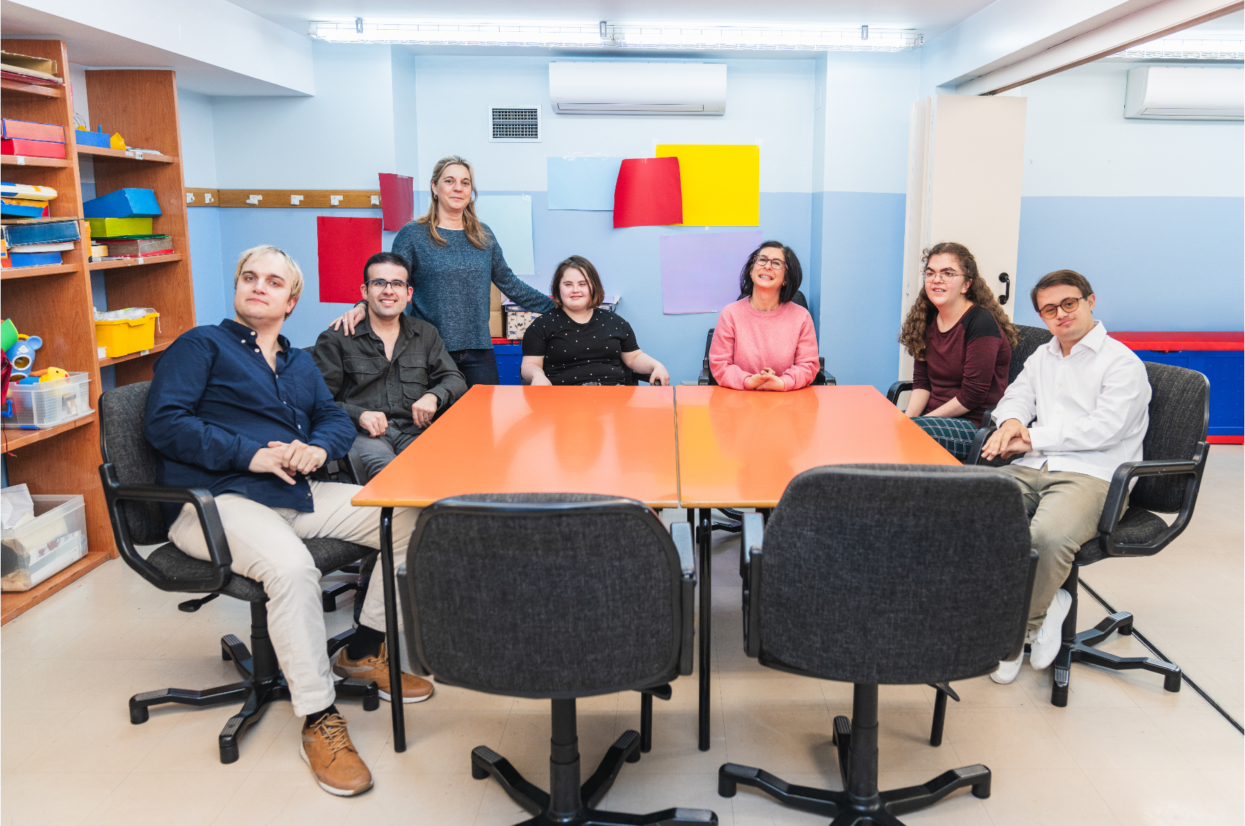 Group of individuals  sitting around a table in a colorful office setting